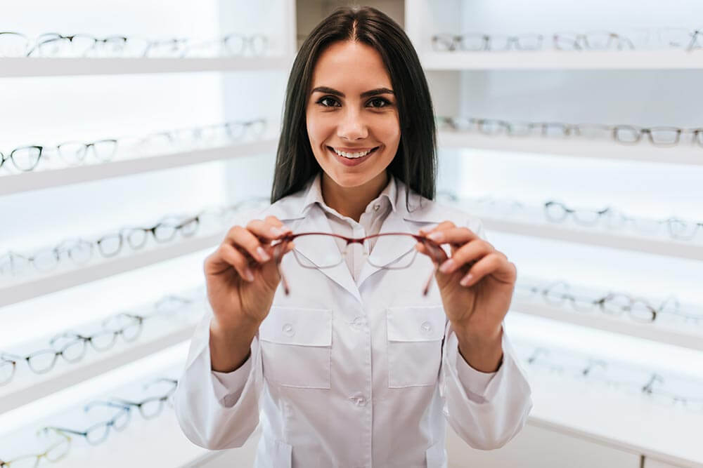 Smiling woman holding glasses in a optical shop